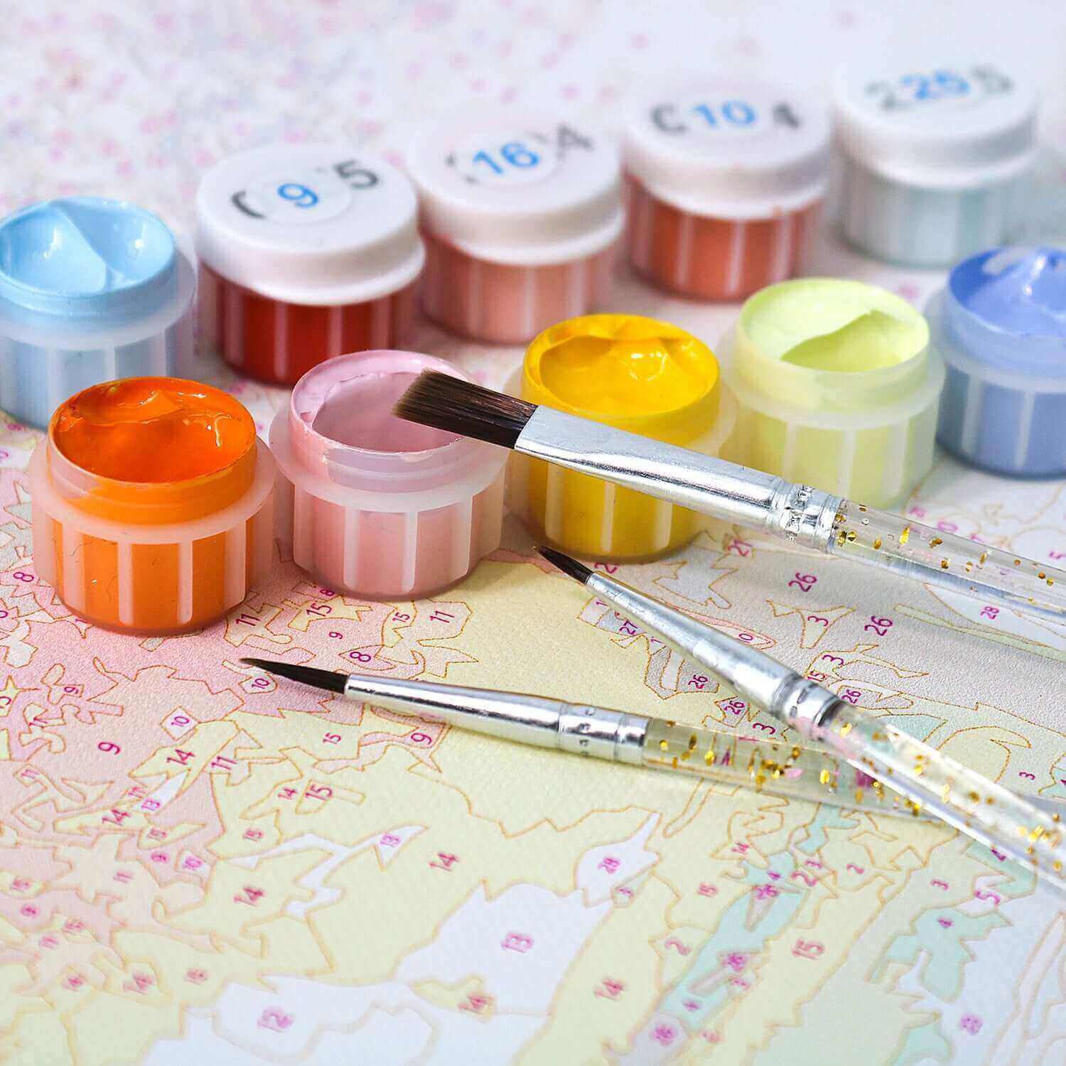 Paint by numbers kits with vibrant paint pots and brushes on a numbered canvas for creative sessions.